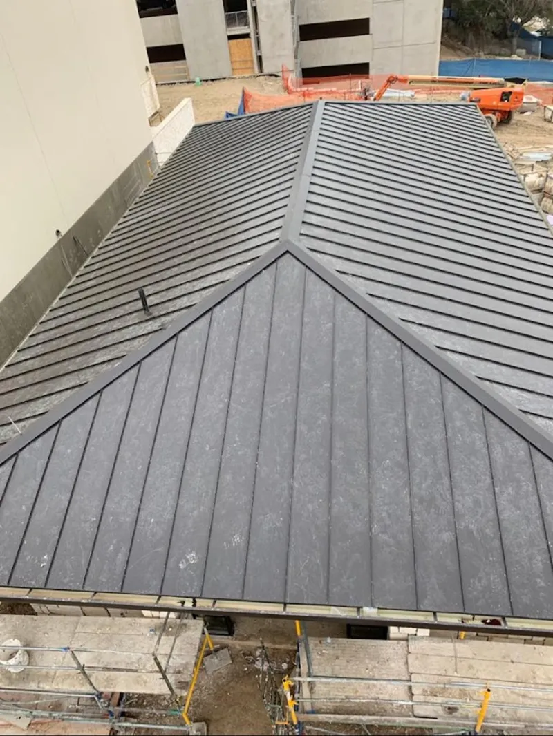 Commercial metal roof construction with crane equipment in Fair Lakes